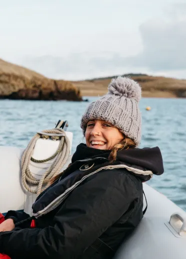 woman on rib boat wearing a wooly hat smiling.