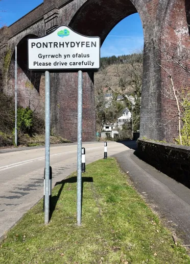 arwydd ffordd 'Pontrhydyfen' gyda thraphont yn y cefndir.