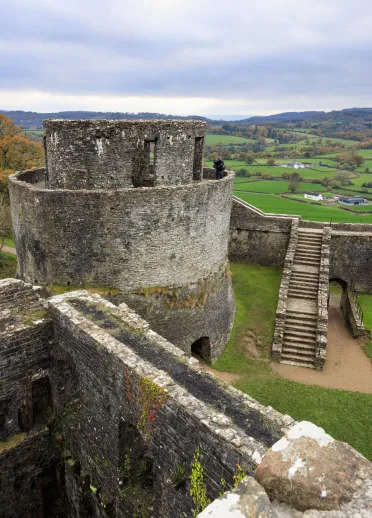 castell gyda thŵr crwn a chefn gwlad o’r awyr.