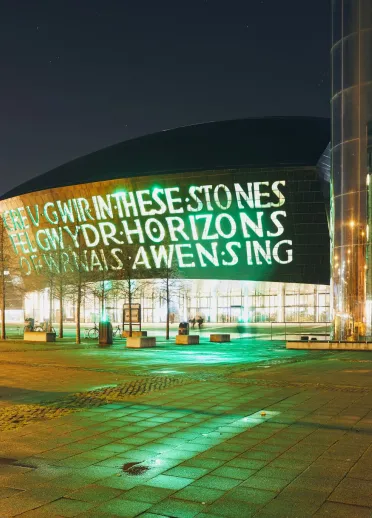 Exterior of Wales Millennium Centre and the water tower on Roald Dahl pass at night.