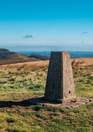 Plinth carreg ar ben mynydd gyda golygfeydd pellgyrhaeddol.