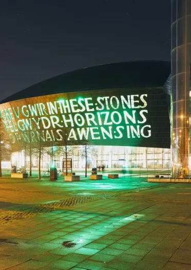 Exterior of Wales Millennium Centre and the water tower on Roald Dahl pass at night.