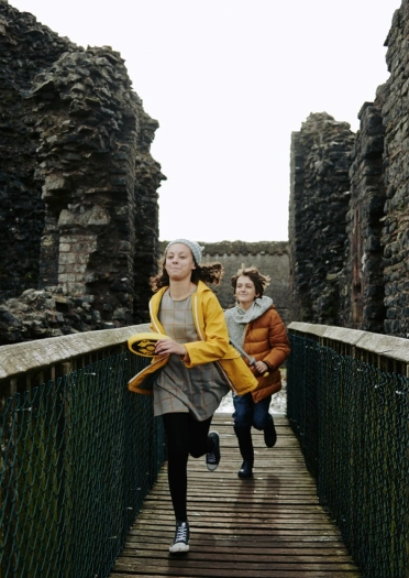 Dau blentyn yn rhedeg ar draws pompren yn syth at y camera