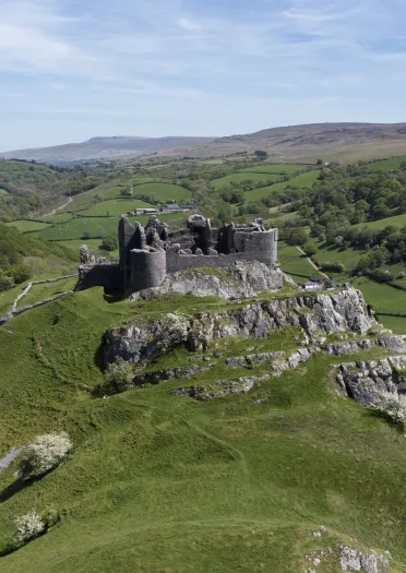Adfeilion castell yng nghefn gwlad ar ymyl clogwyn.