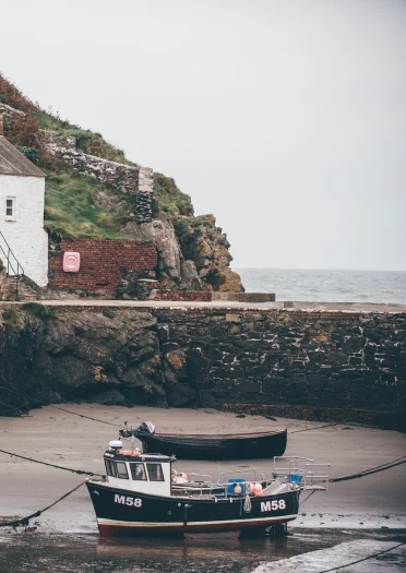 Cwch bysgota a thŷ bach gwyn ym Mhorthgain