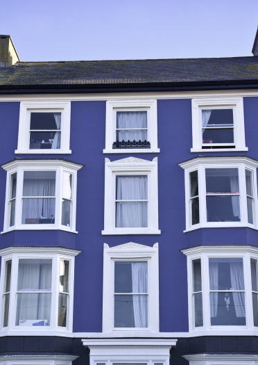 Llun agos o adeilad glas llachar ar brom Aberystwyth