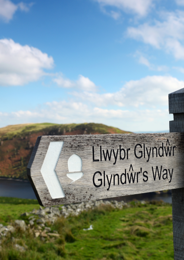 Arwydd Llwybr Glyndŵr gyda Llyn Clywedog a bryniau yn y cefndir