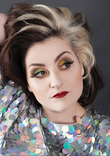 Llun o'r comediwr Kiri Pritchard-McLean mewn dillad sgleiniog