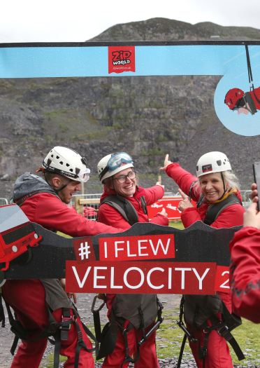 Pedwar person yn cymryd hunlun yn Velocity Zip World.