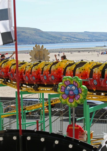 Taith ffair gyda thraeth tywodlyd yn y cefndir.
