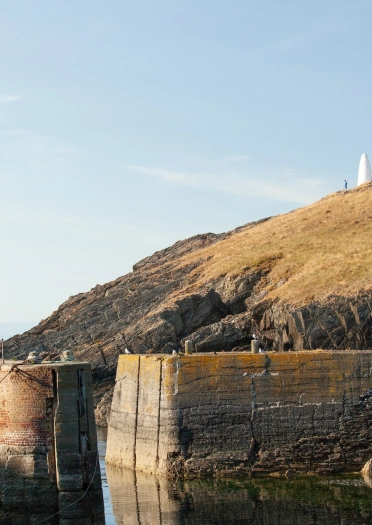 Harbwr bychan â waliau yn ymestyn allan i’r môr.