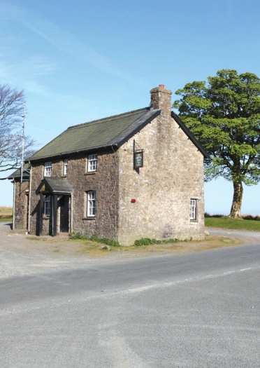 Adeiladau hen gydag ochr ffordd gyda choeden yn y cefn