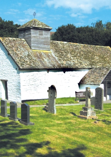 Adeilad gwyn gyda beddau o gwmpas