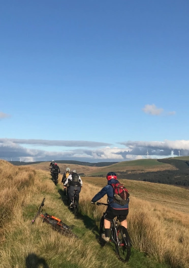 Beicwyr mynydd ar lwybr ar ochr bryn.
