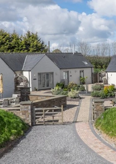 Y tu allan i grŵp o fyngalos gwyliau wedi'u paentio'n wyn.