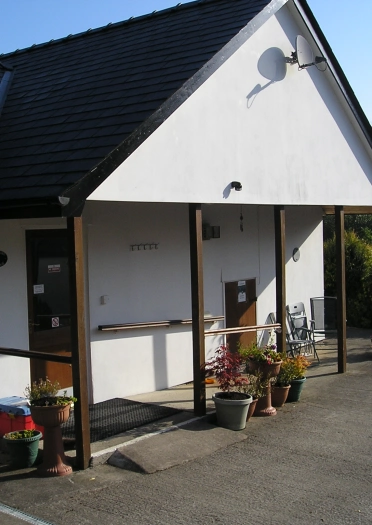 Tu allan i fwthyn gwyliau wedi'i baentio'n wen. 