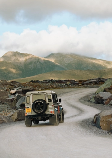 Land Rover yn gyrru ar hyd ffordd lychlyd mewn chwarel lechi.