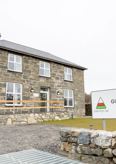 A large stone house with the Glan-llyn Isa’ sign outside.