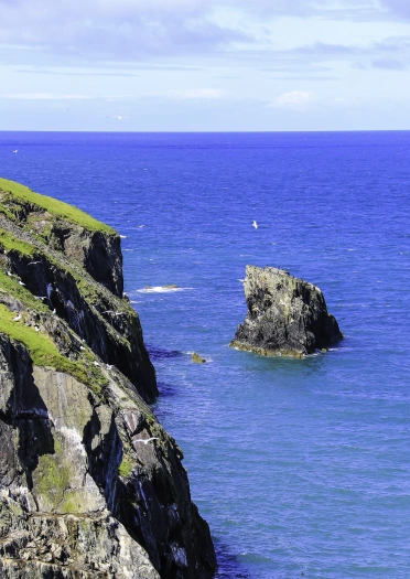 Golygfeydd o ben craig dros fôr glas dwfn.
