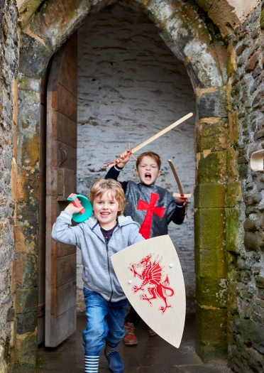 Dau blentyn yn smalio bod yn farchogion mewn castell.
