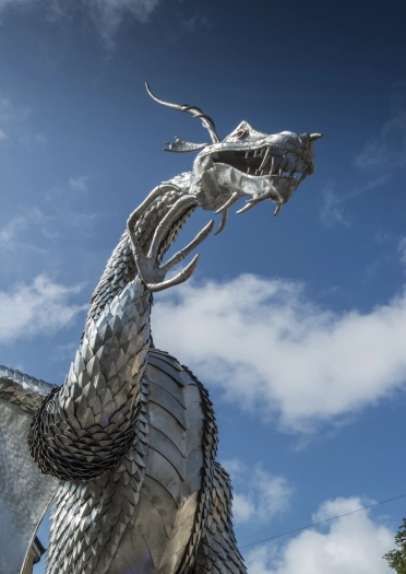 Cerflun draig ddur mawr yng nghanol tref.