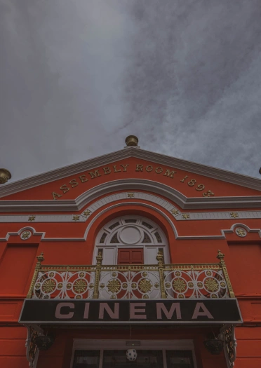 Sinema wedi’i phaentio’n goch tywyll gyda balconi addurnedig uwchben drysau’r fynedfa.