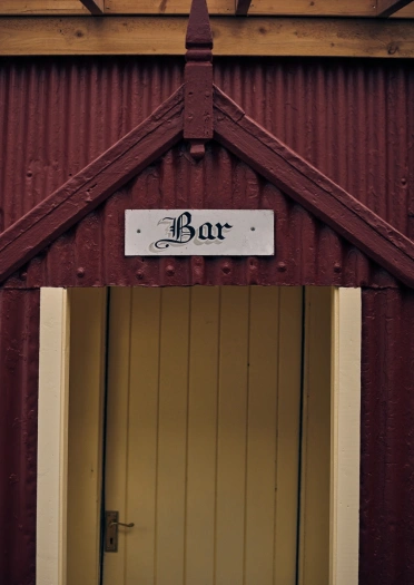Arwydd bar ar ddrws tafarn wedi'i greu o sinc coch