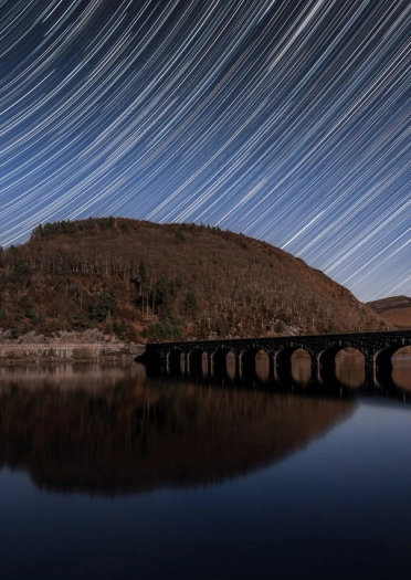 Llwybrau sêr uwchben argae.