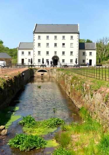 Y tu allan i adeilad gwyn gyda nant.