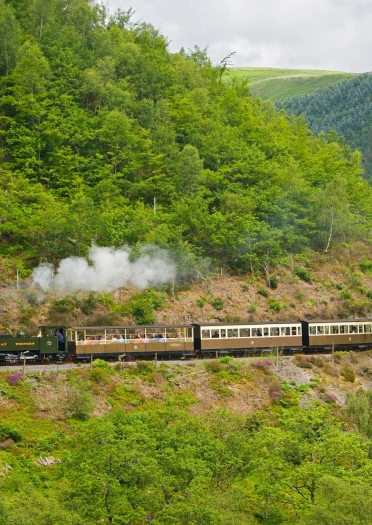 Tren stêm yn trafeilio trwy ganol cefn gwlad