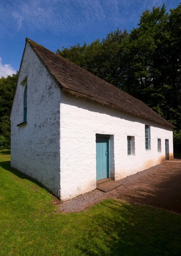 Adeilad gwyn gyda drws pren glas