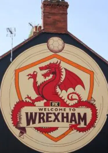 Arwydd ar ochr adeilad 'Welcome to Wrexham' a draig goch.