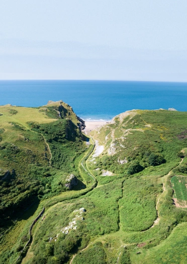 Llun o’r awyr o ddyffryn, gyda llwybr yn arwain at gildraeth bychan wrth y môr.
