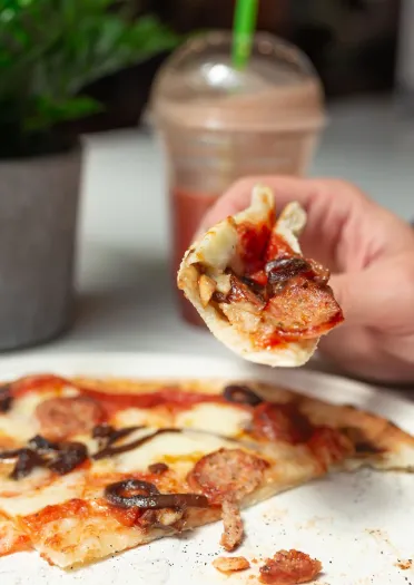 Rhywun yn mwynhau pizza bendigedig