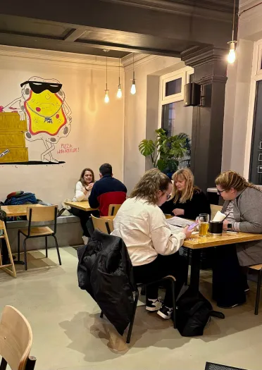 Bobl yn bwyta mewn caffi pizza.