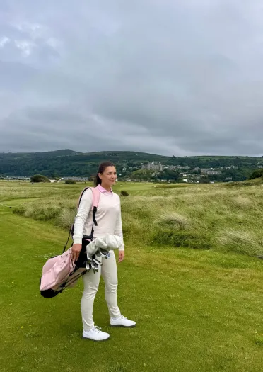 Menyw gyda bag golff ar gwrs golff