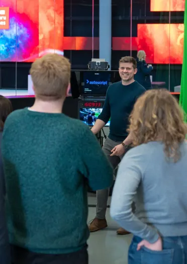 Alt: Tywyswr taith yn esbonio rhywbeth i grŵp o bobl.