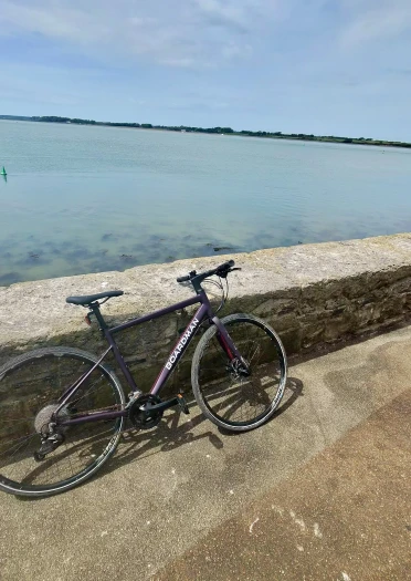 Road bike leaning against a stone sea wall in Caernarfon overlooking the calm waters of the Menai Strait