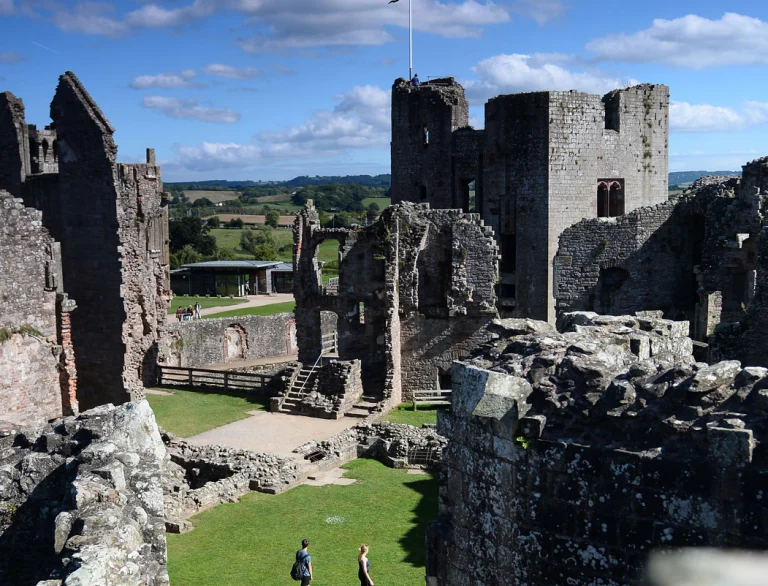 Pâr yn cerdded drwy diroedd Castell Rhaglan yn Ne-Ddwyrain Sir Fynwy.