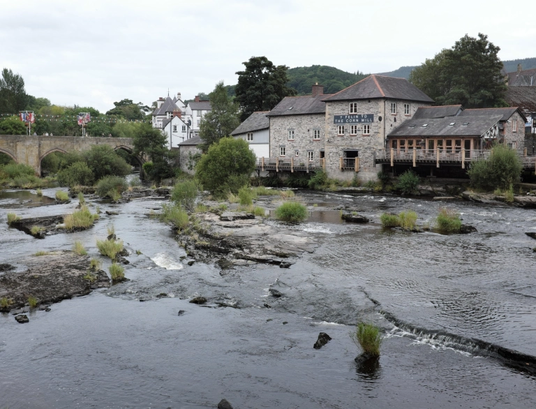 Tafarn â dec y tu allan yn edrych dros afon lydan, fas.