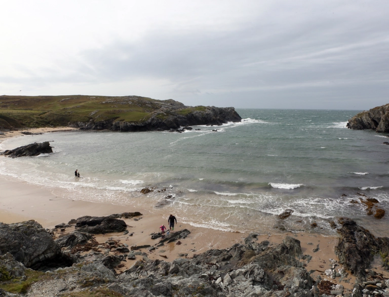 pobl yn cerdded ar draeth.