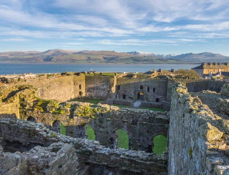 Golygfa o’r awyr o furiau castell a’r môr tu draw.
