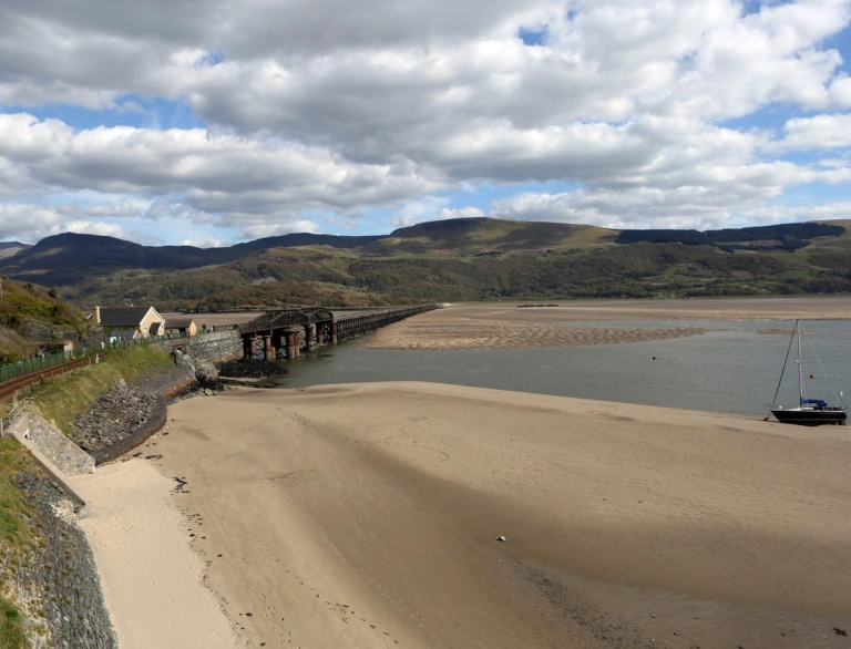Llun o'r awyr o draeth a phont dros yr Aber.