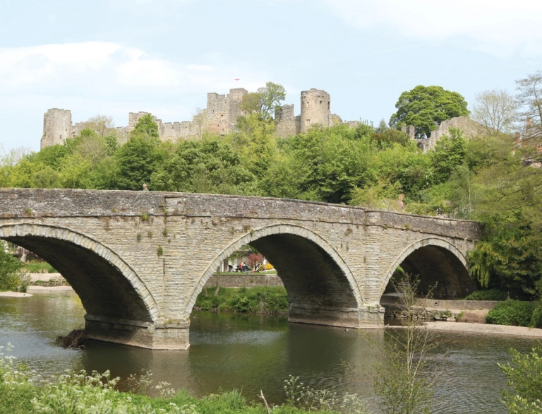 Pont dros afon gyda castell yn y cefndir