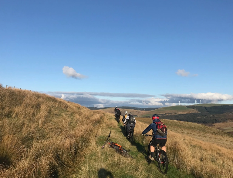 Beicwyr mynydd ar lwybr ar ochr bryn.