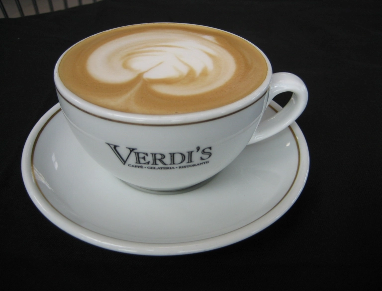 Cup of coffee with Verdi's on cup and saucer.