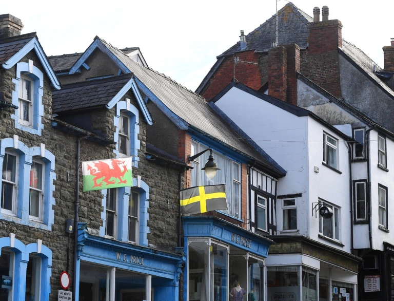 Stryd yn llawn o siopau gyda baneri Cymru yn cyhwfan.