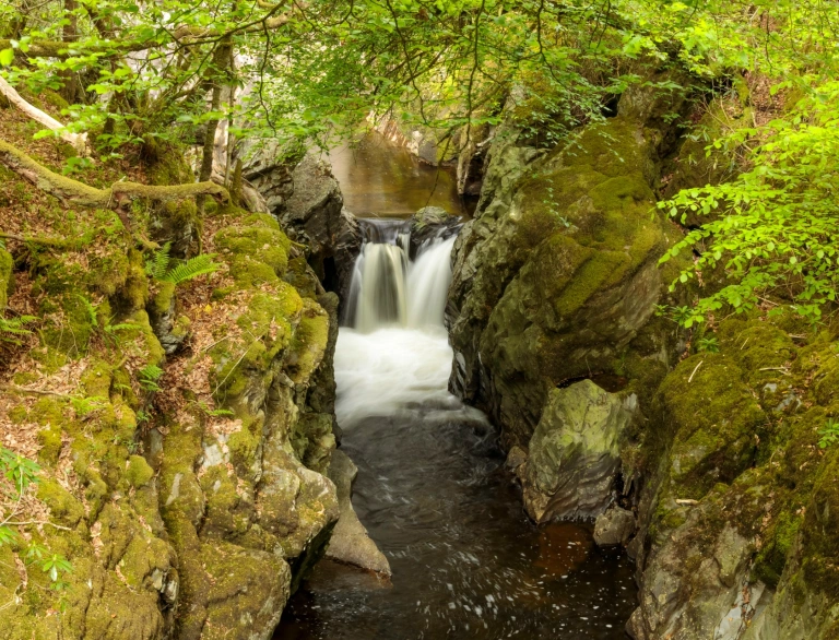 Rhaeadr yn llifo drwy ddyfnant gul.
