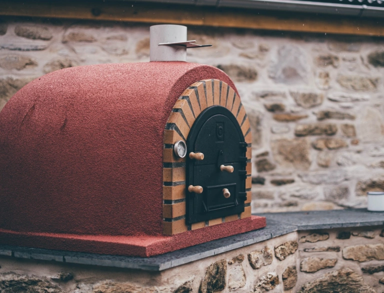 Popty pizza coch tu allan ar wal gerrig.