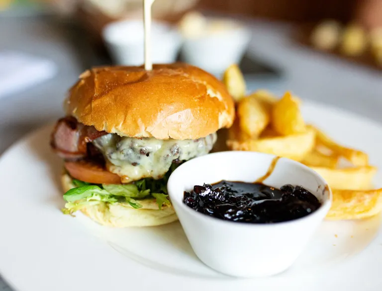 Byrger a sglodion ar blât gyda saws mewn potyn.